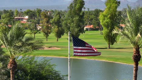 bandera estadounidense ondeando frente a un lujoso campo de golf con palmeras en el suroeste de los estados unidos