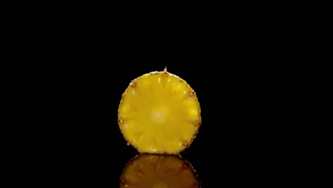 piña en rodajas cae sobre la superficie del agua con gotas salpicadas, fondo negro aislado
