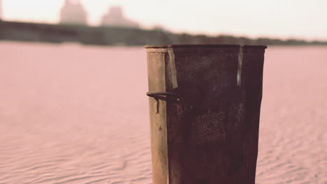 Gray-metal-garbage-bin-or-trash-can-on-the-beach