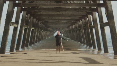 two masked people dance under the legs of a pier