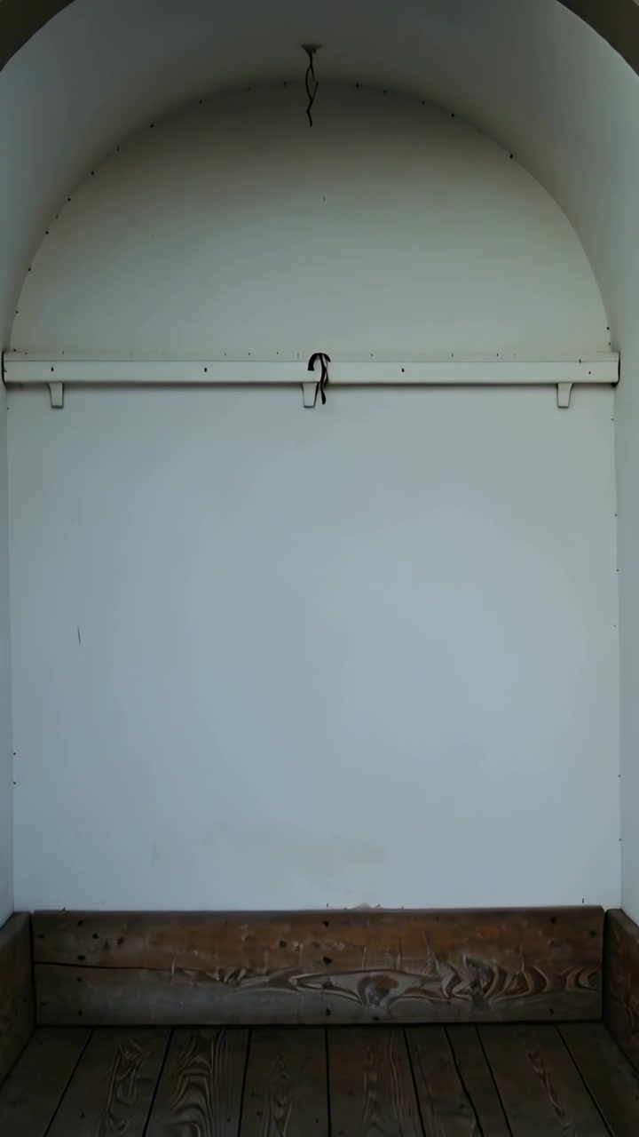 Vertical video: Pulling back camera to reveal bench in recessed niche, showing stone arch and wire
