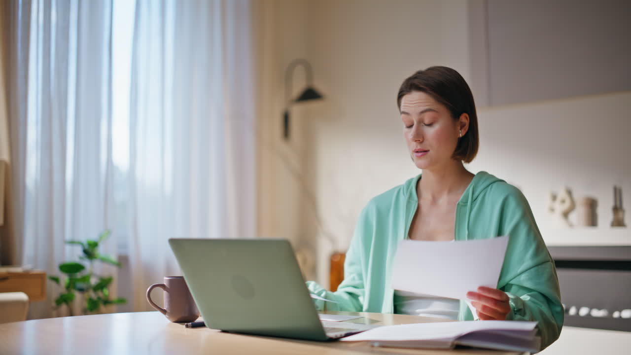 Frustrated freelancer reading papers at remote workspace. Displeased woman