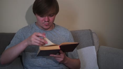 un joven leyendo un libro en un sofá