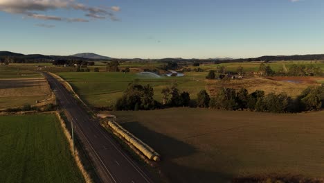 4k60 wide shot of idyllic tasmanian landscape with rural road and green fields, mountains in the background