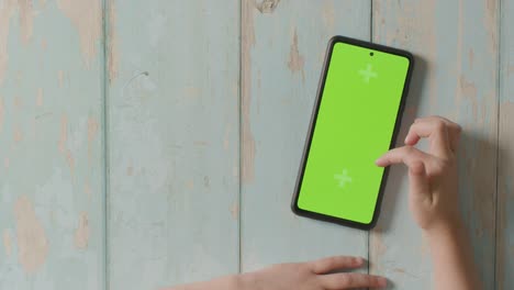 overhead studio shot of child scrolling on green screen mobile phone 2