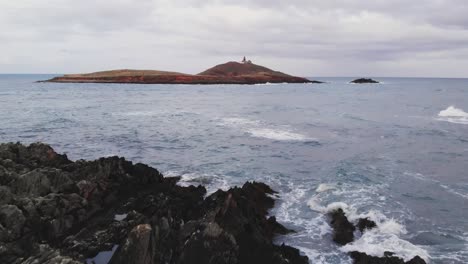 Young-female-hiker-walking-downstairs-on-cliff-over-wavy-sea