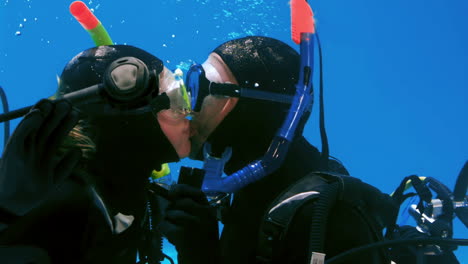 couple in scubas diving kissing in the pool