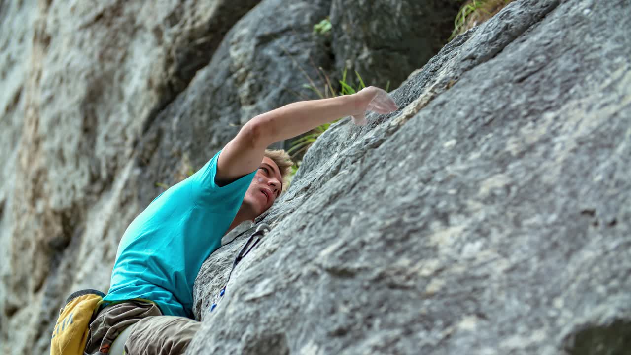 Slow motion closeup shot of a young man rock climbing on a big rock in Burjakove Peci, Slovenia