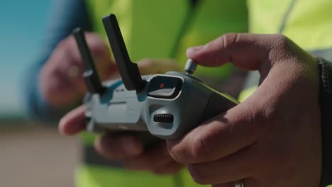 persona que sostiene un controlador de avión no tripulado al aire libre en clima soleado, primer plano