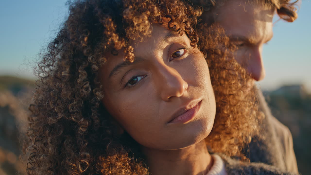 Enamoured woman looking camera at sunset nature portrait. Diverse lovers faces