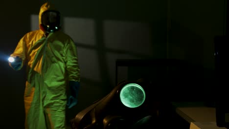 hazmat suit wearing man explores a dark room