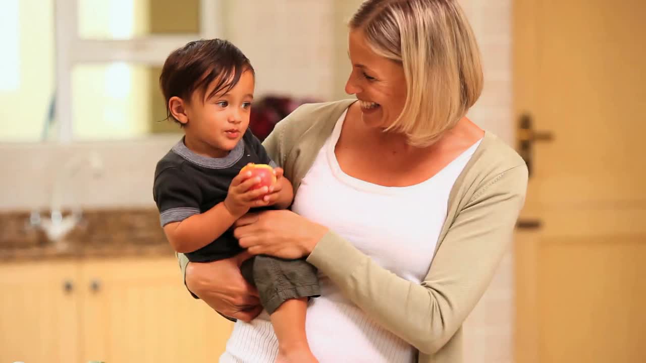 madre sosteniendo al bebé con una manzana y posando