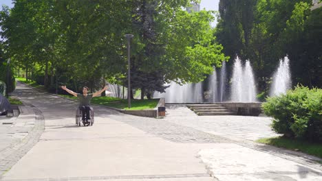 Male-Wheelchair-User-Moving-Alone-On-The-Street,-His-Wheels-Turning.