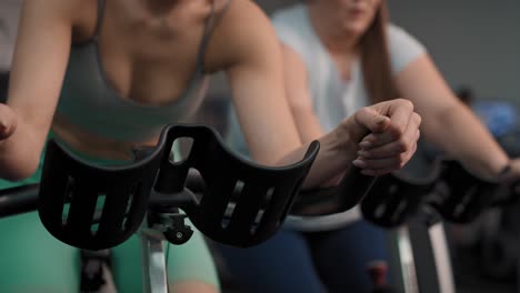 two caucasian women ride a bikes at the gym.