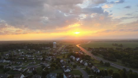 drone flying towards the watertower in clarksville revealing a beautiful sunrise with clouds in the sky