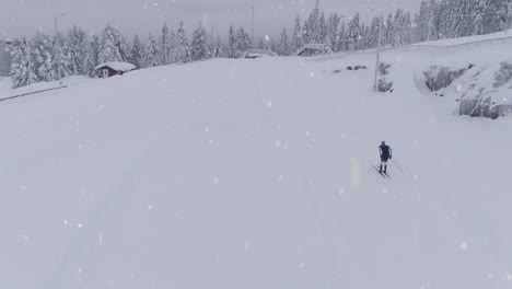 people training cross country skiing during snowfall, aerial follow up shot