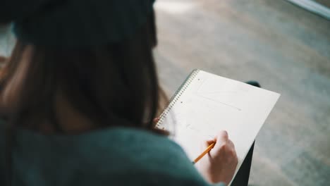 closeup view of a female student taking notes during the lectures. view from the back. shot in 4k.