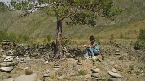 Woman-rests-in-pine-tree-shadow-among-stone-pyramids