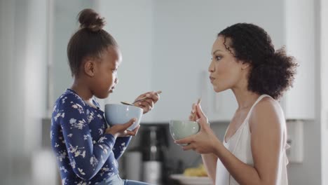 Glückliche-Afroamerikanische-Mutter-Und-Tochter-Beim-Frühstück-In-Der-Küche,-Zeitlupe
