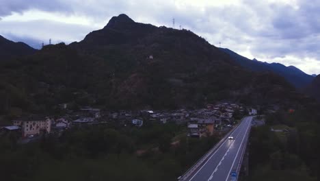 Toma-Aérea-De-Drones-De-Una-Pequeña-Colina-Frente-A-Un-Pintoresco-Pueblo-Alpino-Típico-Italiano