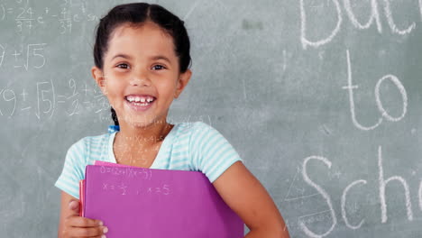 animation of mathematical equations over biracial girl holding files smiling in the class at school
