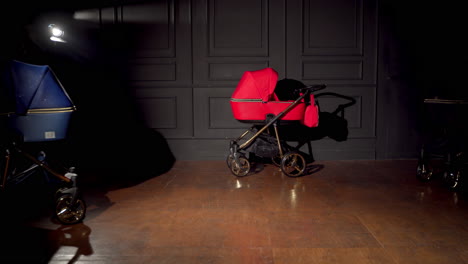 dark room with pushchairs of different colors. baby strollers are pushed to the middle of the room.