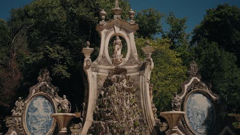 ornate stone fountain with statues in coimbra's parque de santa cruz garden