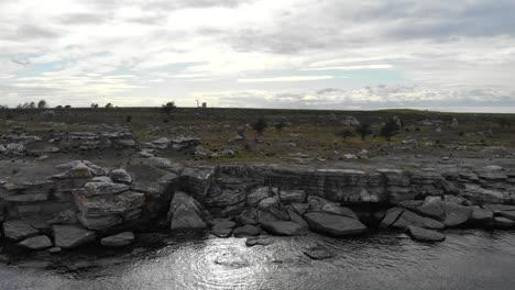 drone flying over rocky baltic coastline near asunden rauk field sweden
