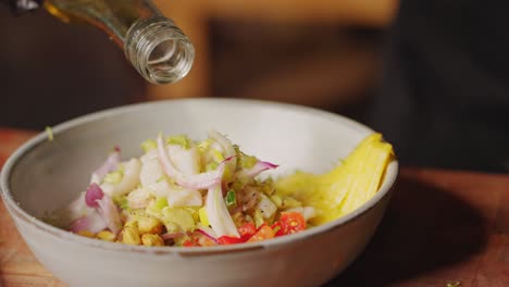 preparation of ceviche - cinematic slow motion close up shot of a chef drizzling extra virgin olive oil into a bowl of ingredients