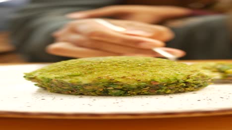 person eating pistachio dessert with a spoon