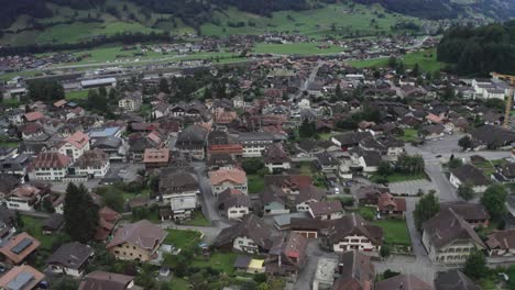 cámara drone que va por encima de edificios de gran altura y de baja altura muchos vehículos de cuatro ruedas y bicicletas que van en la carretera entre los edificios