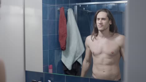 man checking himself in the bathroom mirror