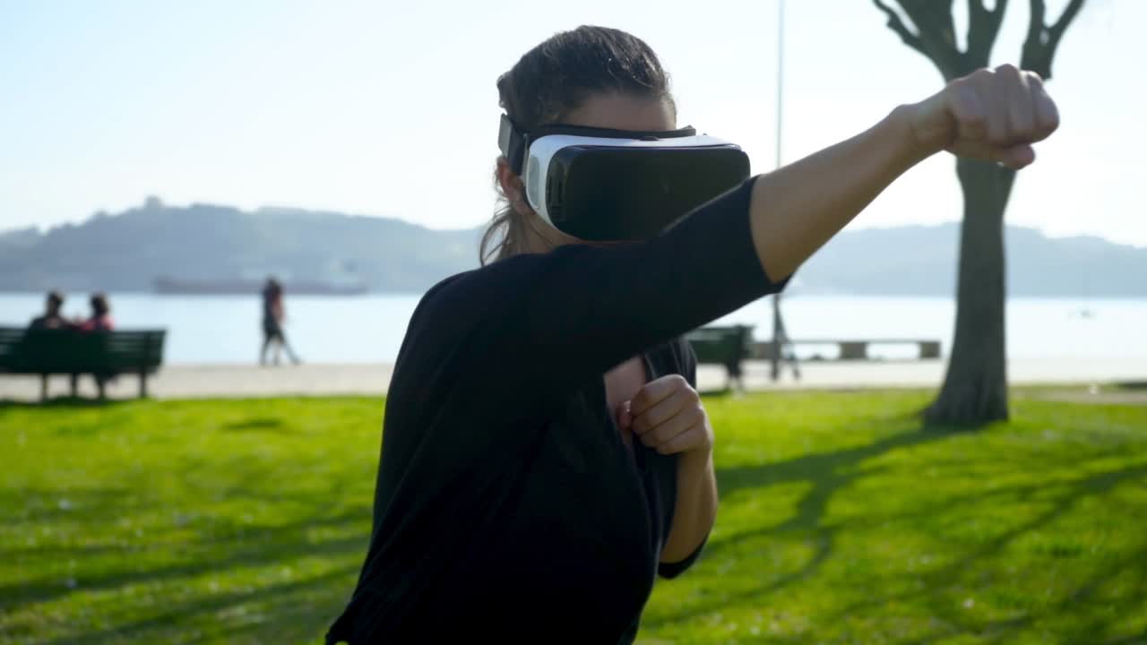 Donna atletica con visore VR che fa boxe all'aperto