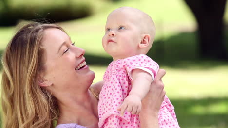 happy mother playing with her baby girl in the park