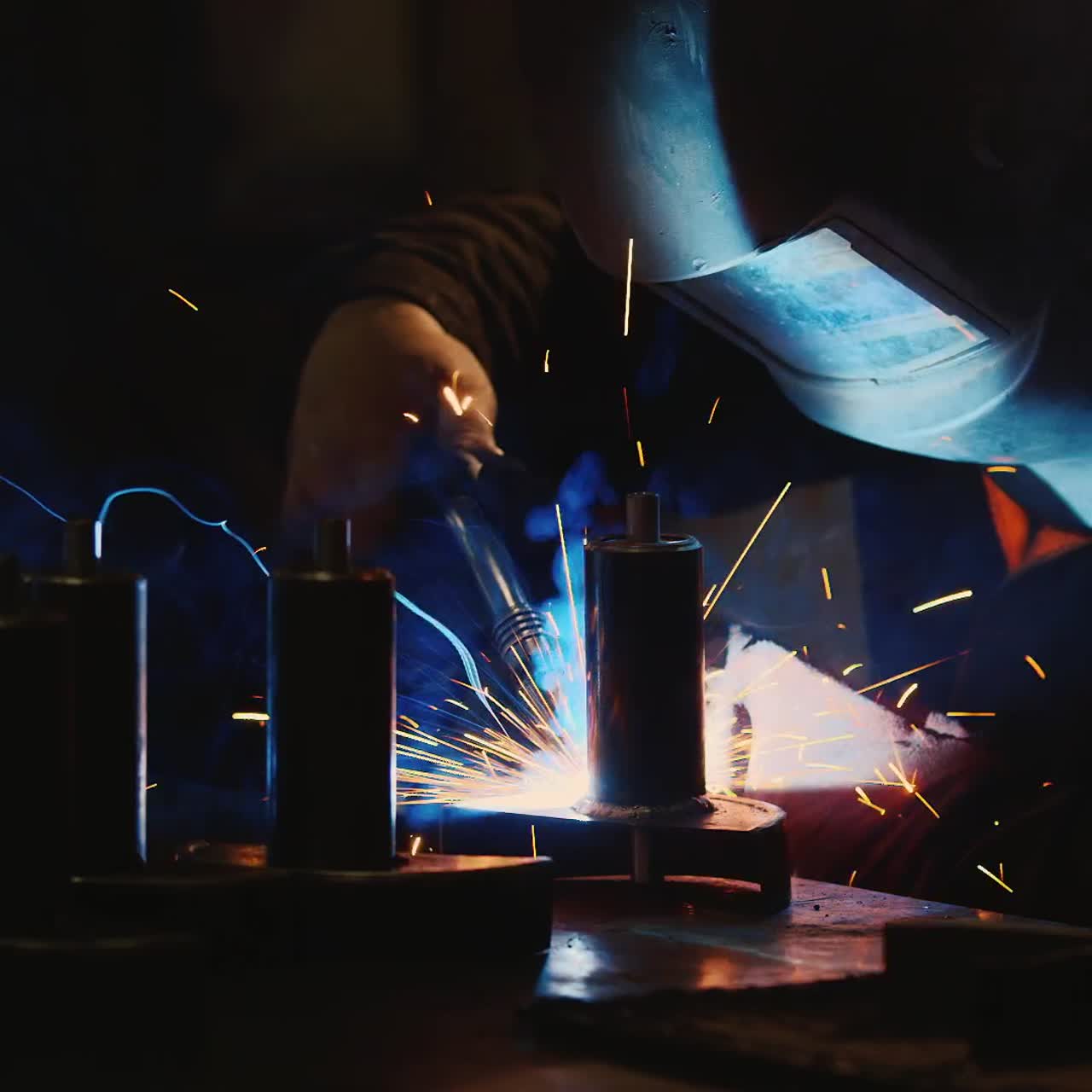 A welder in a protective helmet and clothes welds as sparks fly 8