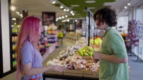 Close-up-of-a-girl-with-pink-hair-dancing-with-her-brunette-boyfriend-in-bright-clothes-while-shopping-in-a-grocery-store