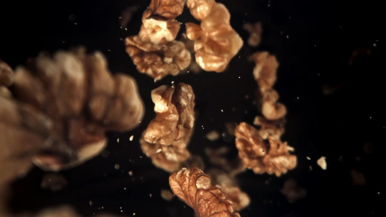 Walnut Pieces Falling in Slow Motion on Black Background