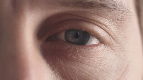 ojo azul masculino de cerca parpadeando mirando el enfoque de la pupila de la cámara