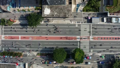 dron aéreo de arriba hacia abajo a vista de pájaro a la derecha toma de camión de la famosa avenida paulista en el centro de são paulo con rascacielos gigantes que rodean una calle cerrada con multitudes de personas caminando