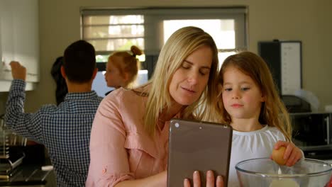 mother and daughter using digital tablet while preparing food 4k