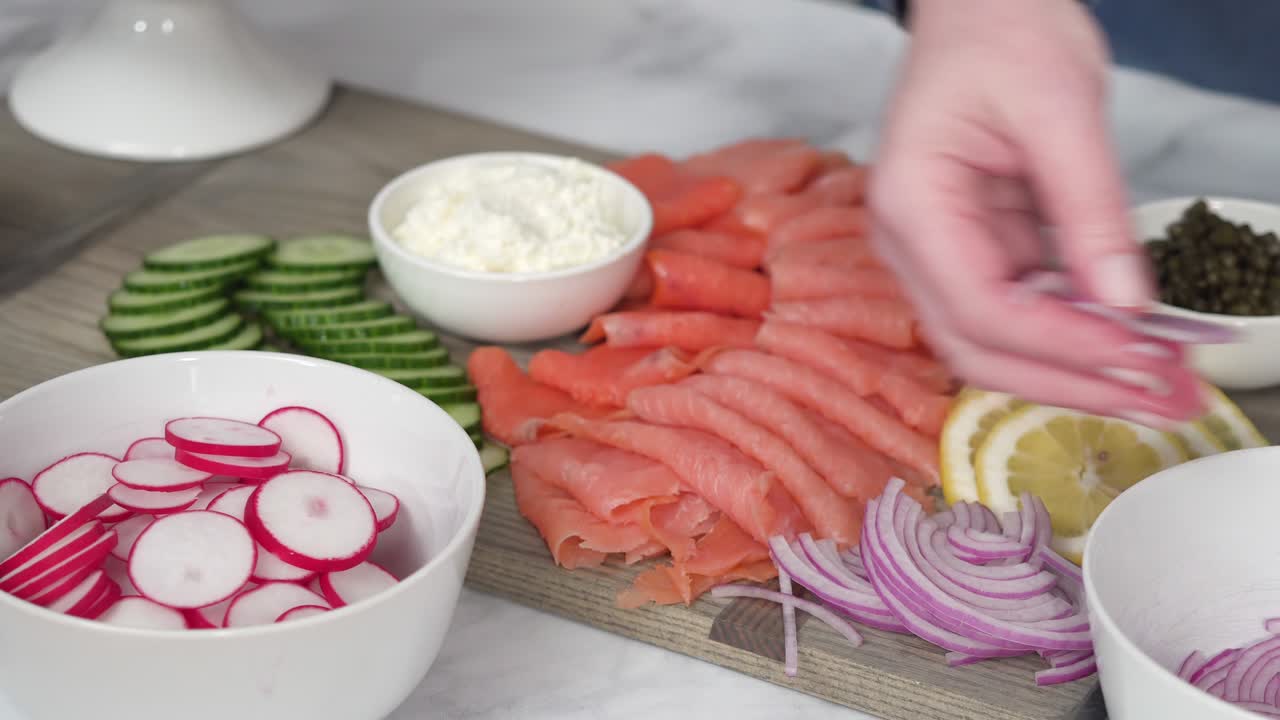 montando una mesa de brunch de bagels con salmón ahumado y verduras frescas.