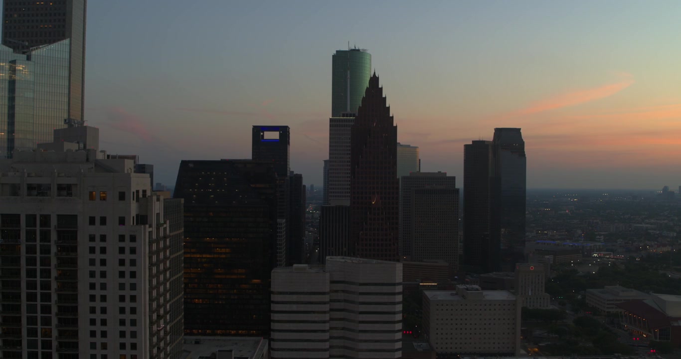 Vista aérea con dron del centro de Houston, Texas, mostrando modernos rascacielos y torres de oficinas durante el atardecer y la hora azul.