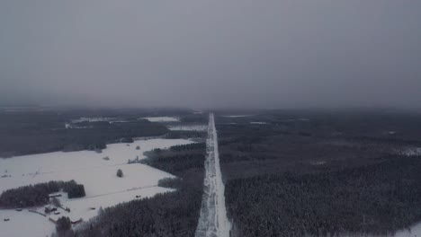 aerial view of power line road in snowy cold deep forest