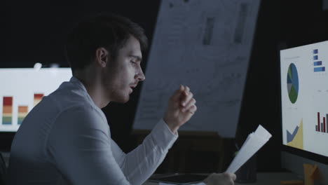 angry business man throwing document paper on computer table in dark office