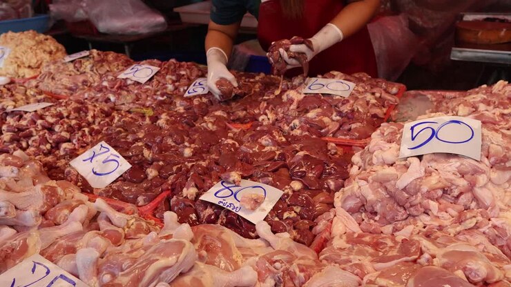 Mani che sistemano varie parti di pollo in esposizione