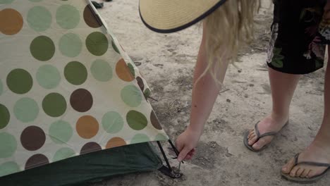 taking pegs off to pack up a tent blonde woman camping