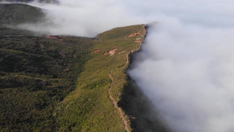 Volando-Sobre-Verdes-Colinas-Y-Montañas-Por-Encima-De-Las-Nubes-En-Un-Claro-Día-De-Verano,-Hermosos-Paisajes-En-4k