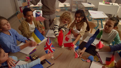 estudiantes multiétnicos con banderas internacionales en las manos en una mesa redonda