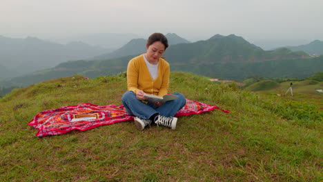 young-woman-reads-perched-on-peaceful-mountain-top-while-the-camera-orbits-around-her