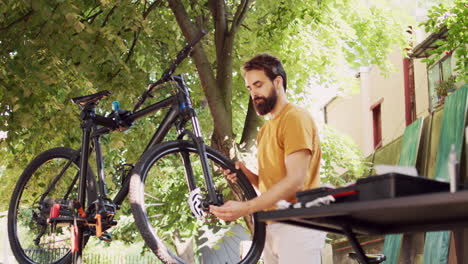 male examining bicycle front set in yard